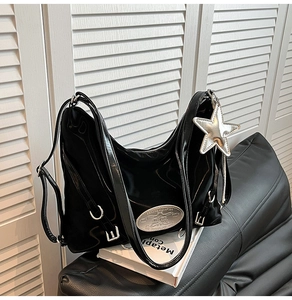 Detail shot of black patent leather hobo bag with silver star charm and metallic hardware