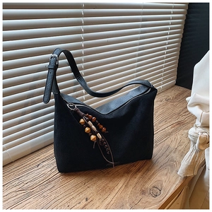 Detail of vintage tote bag with elegant beaded pendant and textured suede material