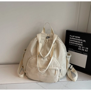 Detail of off-white nylon tote backpack featuring large front pocket and side drawstring pockets
