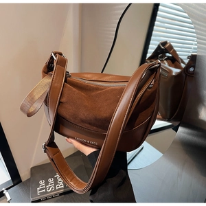 Detail of the caramel brown saddle bag showing suede patchwork and wide woven handle