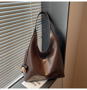 Detail of dark brown leather tote bag with vintage texture and plush dog charm