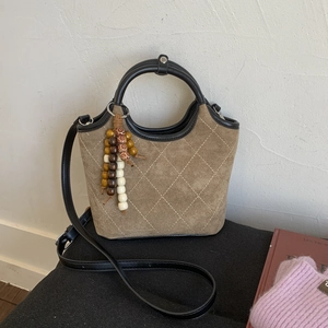Sac seau rétro en daim marron avec surpiqûres losanges, poignées rondes et charms