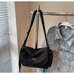 Detail of minimalist black nylon messenger bag with adjustable strap and brand label