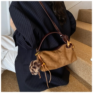Brown suede pillow bag with leopard print pompom and leather tassels detail closeup