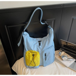 Dettaglio borsa a tracolla blu in nylon con tasca gialla a coulisse e tracolla regolabile
