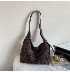 Close-up of leopard print hobo bag with laptop and headphones in office setup