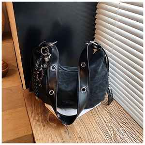 Detail view of black vintage hobo bag featuring large silver eyelets and tassel charms