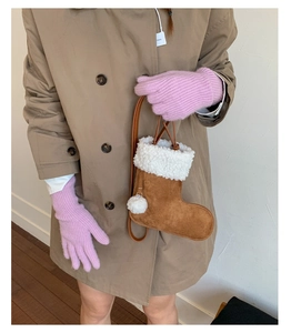 Detailed close-up of brown suede Christmas stocking shaped bag with white fleece trim and pompom