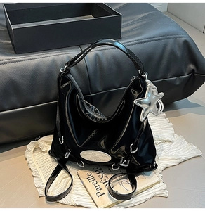 Detail view of the black glossy crescent Hobo bag featuring a stylish star charm