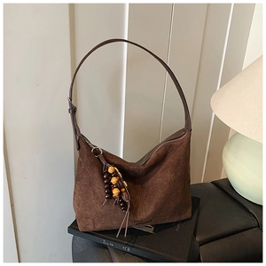 Close-up of vintage brown suede tote bag with wooden bead tassels and fringe detail