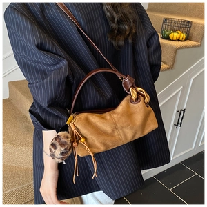 Brown suede crossbody bag with gold chain strap and leopard print fur ball accessory