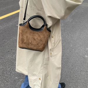 Gros plan du sac seau en daim marron avec matelassage en losanges et lanières en cuir noir