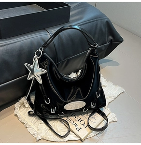 Detail of black glossy shoulder bag with silver star charm and stylish white patch