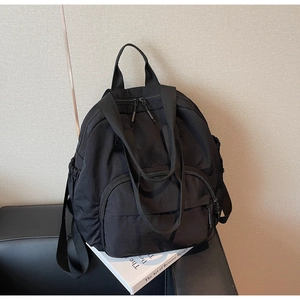 Detailed side view of a black nylon backpack with multiple zipper pockets and side pockets
