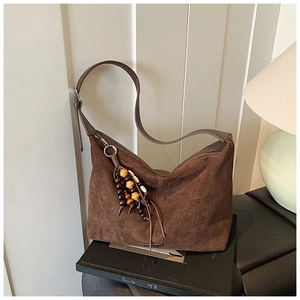 Detail of brown suede tote bag with decorative wooden and resin beaded tassel pendant