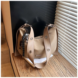 Detail view of a beige hobo bag on a book showing silver eyelets and leather logo patch