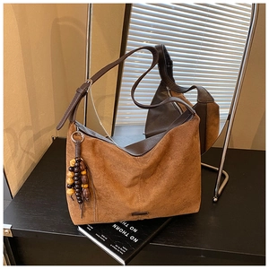Close-up of brown suede hobo bag with vintage wooden beaded tassel detail and leather strap