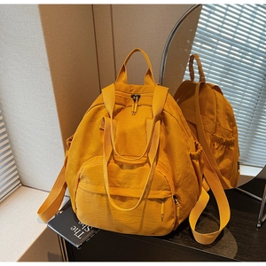 Detail view of ginger yellow nylon backpack with front pocket and durable dual zippers