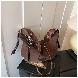 Close-up of vintage brown tote bag with leather tag, metal grommet strap and boho charm