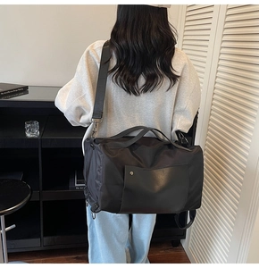 Close-up of black nylon travel duffel bag with leather pocket and adjustable shoulder strap