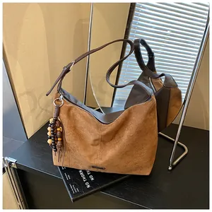Detail of a vintage brown suede tote bag with ethnic wooden bead charm and metal buckle