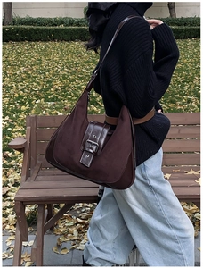 Lifestyle-Foto einer dunkelbraunen Vintage-Halbmond-Tasche mit Lederriemen im Freien