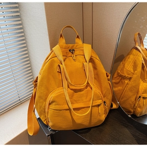 Detail of ginger yellow nylon tote backpack showing multi-pocket design and versatile straps