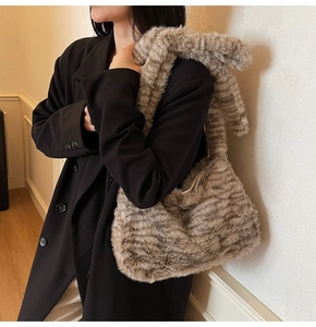Detailed texture of plush tiger print hobo bag with wide shoulder strap on model