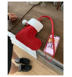 Detail view of red suede Christmas stocking crossbody bag with white faux fur trim and pompom