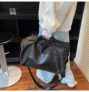 Detail showing high-density black nylon fabric and leather拼接 handle on a large travel bag