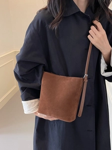 Brown frosted suede bucket bag with adjustable strap and embossed minimalist logo