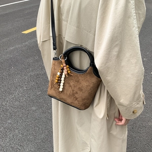 Détails du sac seau en daim marron avec surpiqûres en losange et perles en bois colorées
