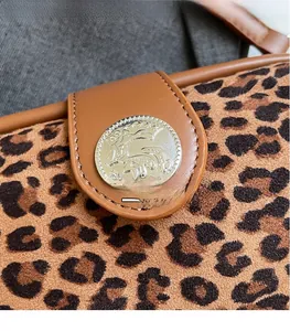 Close-up of leopard print crossbody bag with silver metal buckle and brown leather detail