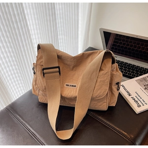 Detail of tan nylon crossbody bag featuring YOU JI BEAR rubber logo and adjustable strap