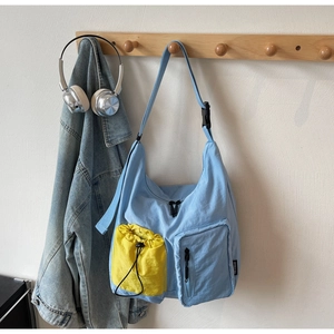 Dettaglio della borsa a tracolla azzurra con tasche gialle a coulisse ed etichetta tessuta
