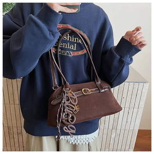 Detail of dark brown matte handbag with long straps and large Bag letter charm