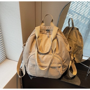 Macro detail of the khaki nylon backpack showing the front pocket and drawstring side pouch