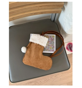 Detailed close-up of a Christmas stocking shaped suede handbag with white faux fur trim