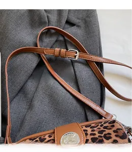 Detail of leopard print bag showing brown leather strap and silver metal buckle adjustment