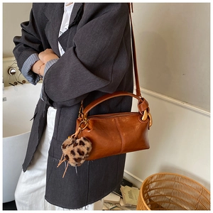 Brown oil wax leather crossbody bag with wide strap and leopard print heart charm