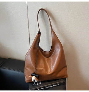 Detail view of brown faux leather hobo bag with a cute white puppy plush charm decoration