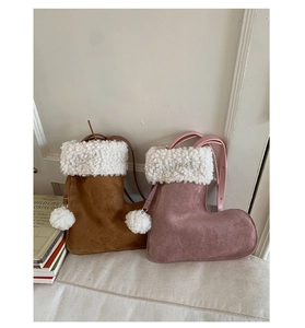 Close-up of boot-shaped suede crossbody bags with white plush trim and fuzzy pom-poms