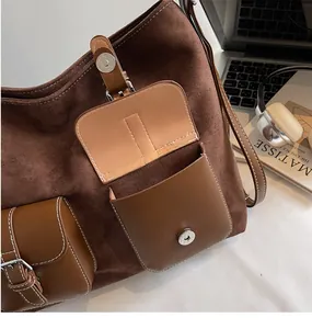 Close-up of brown suede patchwork tote bag featuring functional pockets and magnetic buckle