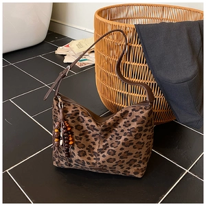 Chic leopard print hobo bag with dark brown strap and beaded tassel on a tiled background