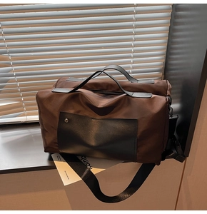Detail of a large brown canvas travel bag with sturdy black straps and metal rivets