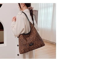 Detail view of mini leopard print tote bag with black leather shoulder strap on model