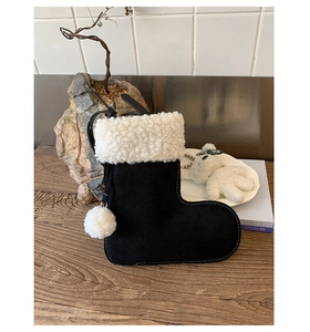 Detail of creative black suede Christmas boot bag with white faux fur and pom-pom charm