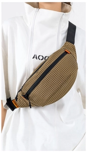 Nahaufnahme der braun karierten Umhängetasche aus Nylon mit orangefarbenem Logo-Etikett