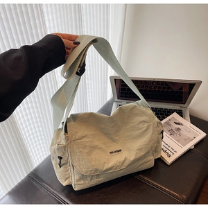 Detailed shot of sage green nylon messenger bag featuring adjustable strap and logo flap