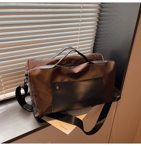 Detail of dark brown travel bag featuring nylon fabric, black handles and metal rivet pocket
